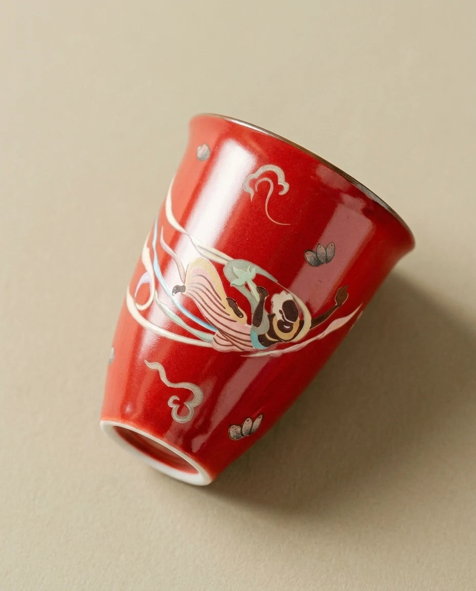 Close-up of the hand-painted Flying Apsara motif on the red porcelain cup